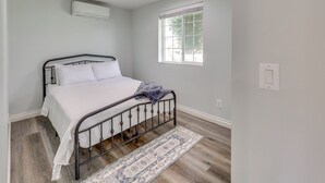 A bedroom with a bed, a window, and an air conditioning unit. - Sleek San Fernando Studio ~ 14 Mi to Universal (San Fernando)