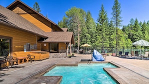 Une cabane en bois avec une piscine, un espace salon extérieur et une forêt en arrière-plan.