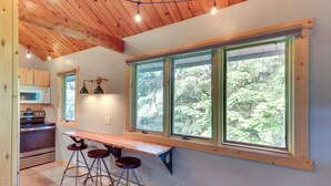 Une cuisine avec une table et des tabourets en bois, un four à micro-ondes et une cuisinière.
