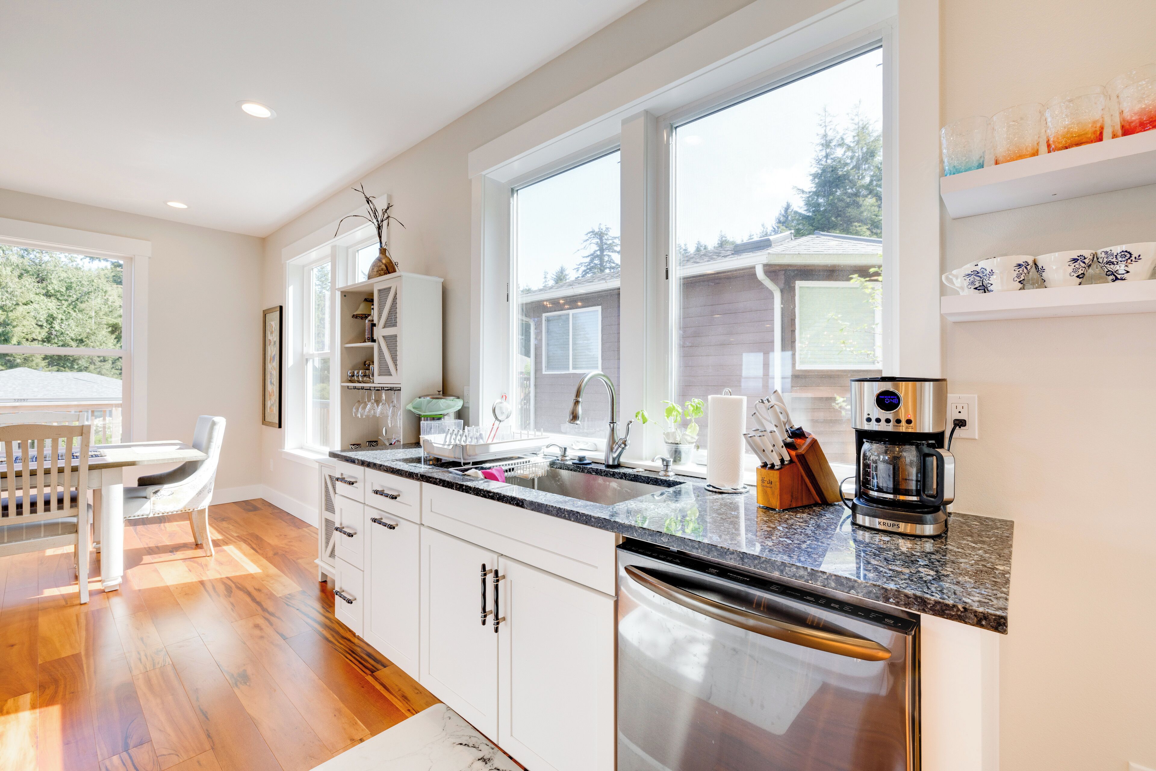 A modern kitchen with white cabinets, a granite countertop, and stainless steel appliances.