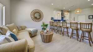 A modern living room with a sofa, a coffee table, and a dining area with wooden chairs and a bar. - Sebring Serenity: Waterfront Retreat w/ Boat Dock! (Sebring)