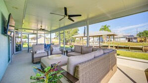 A covered outdoor seating area with wicker furniture, ceiling fans, and large windows offering views of the surrounding area. - Sebring Serenity: Waterfront Retreat w/ Boat Dock! (Sebring)