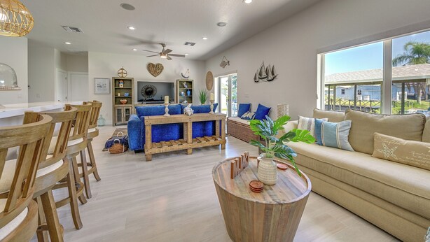 A spacious living room with a wooden dining area, a beige sofa, and a large window offering a view of the outdoors. - Sebring Serenity: Waterfront Retreat w/ Boat Dock! (Sebring)