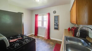 A kitchen with a gas stove, a refrigerator, a sink, and wooden cabinets. - Gary Vacation Rental ~ 5 Mi to Lake Michigan! (Gary)