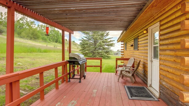 A wooden cabin with a covered porch, a grill, and outdoor seating.