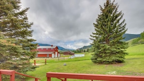 A rural landscape with a red barn, a large evergreen tree, and a grassy field.