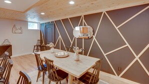 A dining area with a wooden table, chairs, and a decorative wall panel. - Hot Tub, Fire Pit: Pet-friendly Freehold Home! (Freehold)