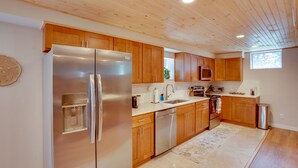 A modern kitchen with wooden cabinets, stainless steel appliances, and a marble countertop. - Hot Tub, Fire Pit: Pet-friendly Freehold Home! (Freehold)
