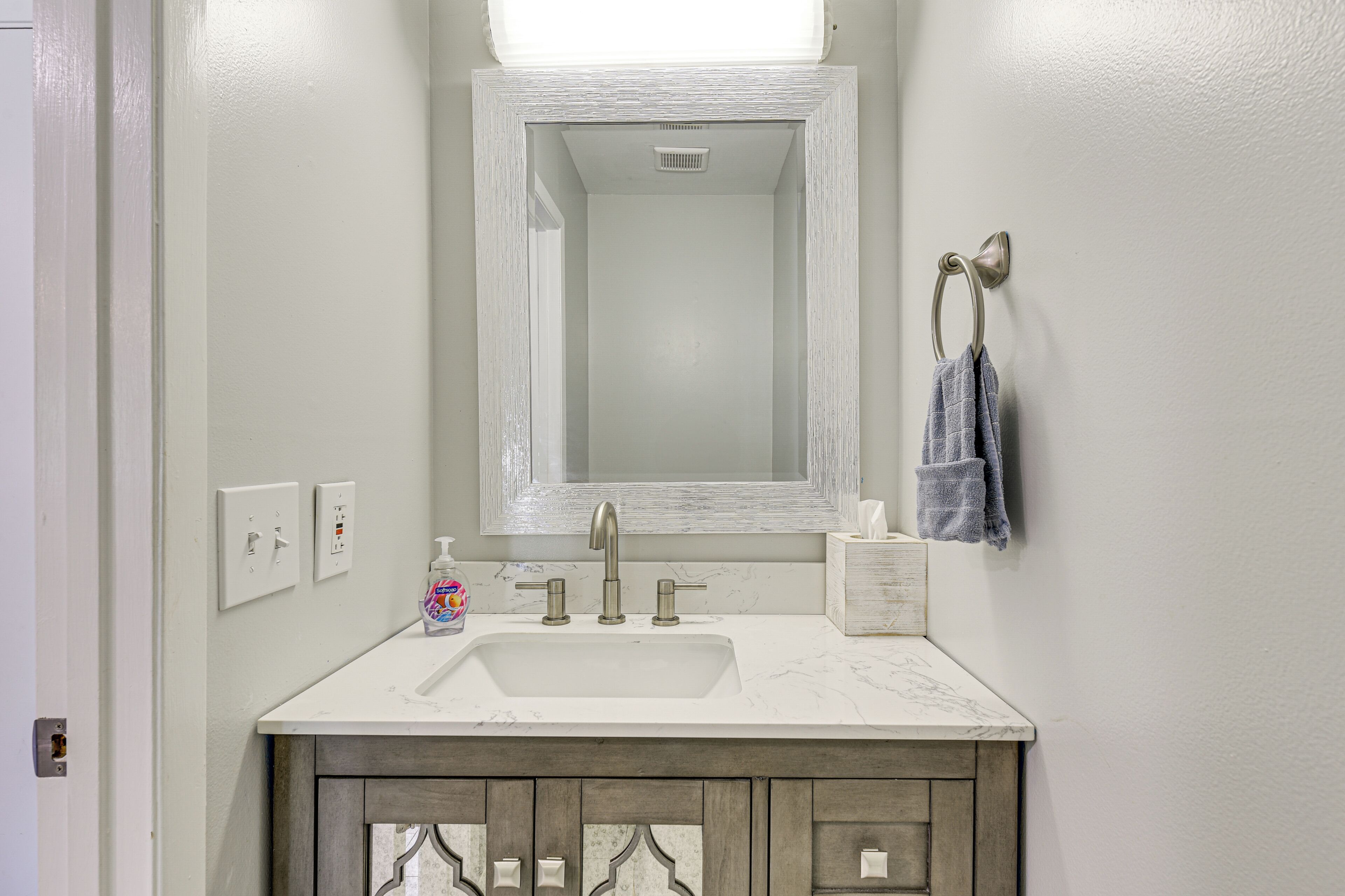 A bathroom with a white sink, a mirror, and a towel rack.