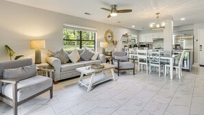 Un salon spacieux comprenant un canapé, des fauteuils et un coin repas avec une table et des chaises.