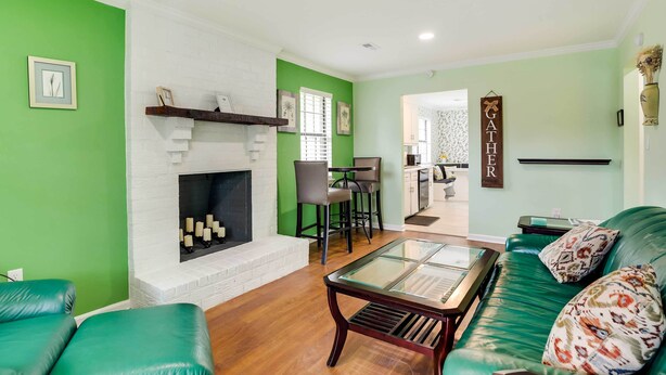 A living room with a fireplace, green walls, a green sofa, and a coffee table.