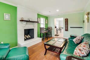 A living room with a fireplace, green walls, a green sofa, and a coffee table. - Vibrant North Charleston Duplex Near Airport! (North Charleston)