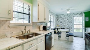 A modern kitchen with white cabinets, stainless steel appliances, and a black countertop.