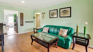 A living room with a green sofa, a glass-top coffee table, and two side tables with vases.
