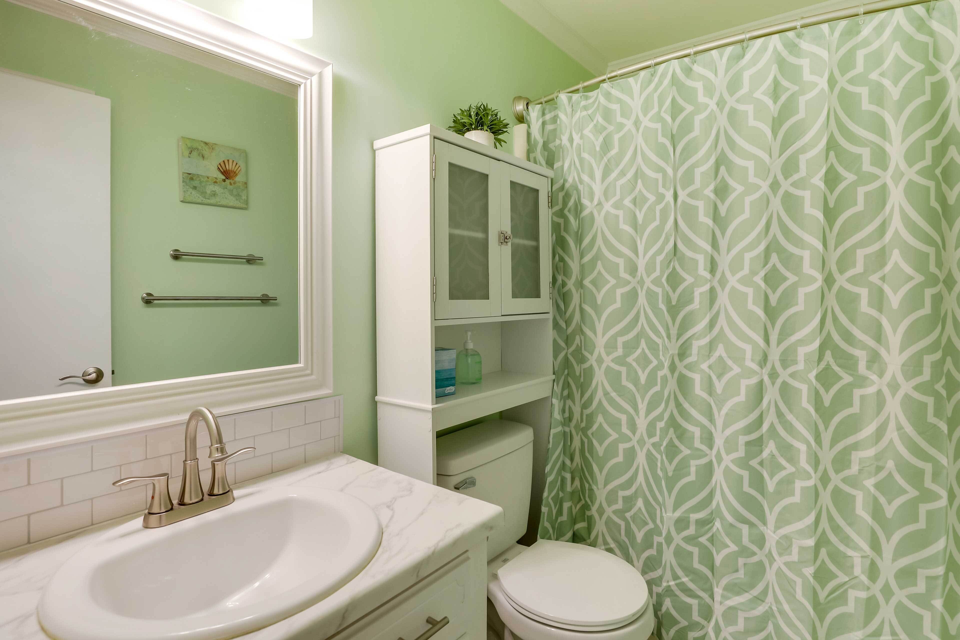 A bathroom with a white sink, a toilet, a cabinet, and a shower curtain with a geometric pattern.