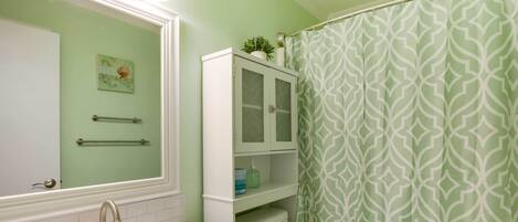 A bathroom with a white sink, a toilet, a cabinet, and a shower curtain with a geometric pattern.