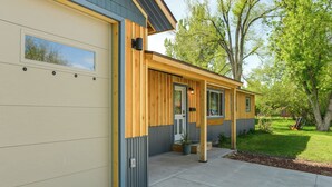 Un edificio moderno con porta garage, rivestimento in legno e un piccolo portico con una pianta in vaso.