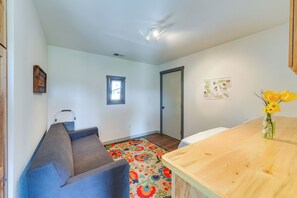 A room with a sofa, a wooden table, a colorful rug, a window, and a door. - Family-friendly Lander Home Rental: Yard, Patio! (Lander)