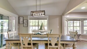 Une salle à manger avec une grande table et des chaises, un lustre et des œuvres d’art encadrées accrochées aux murs.