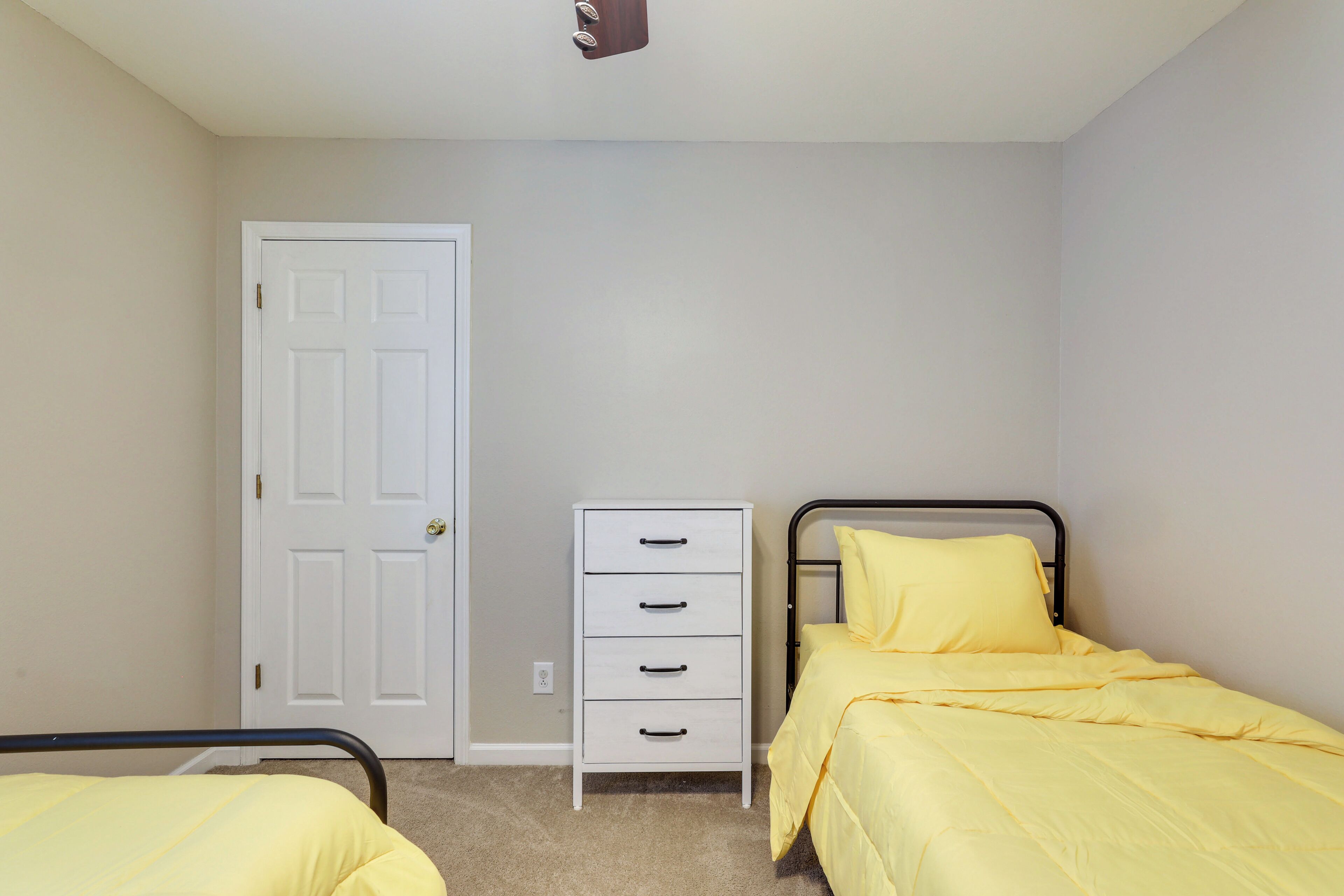 A bedroom with a bed, a dresser, and a door.