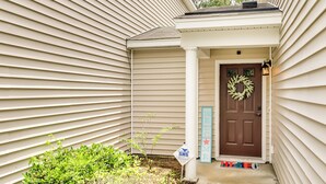A house with a brown front door, a wreath, and a welcome sign.