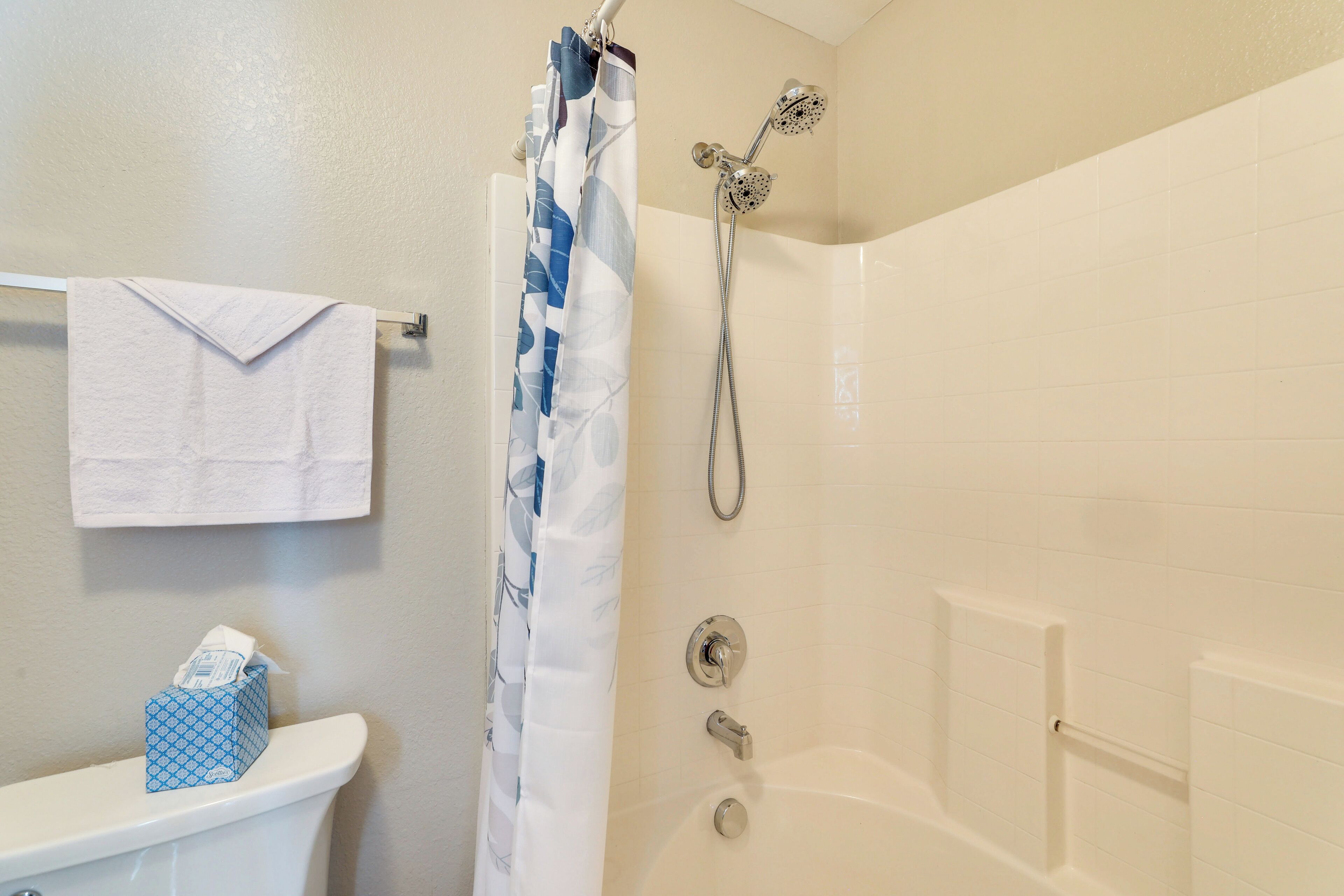 A bathroom with a toilet, a shower curtain, a towel rack, and a tissue box.