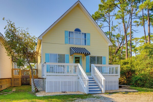 A two-story house with a front porch, a staircase, and a small deck area.