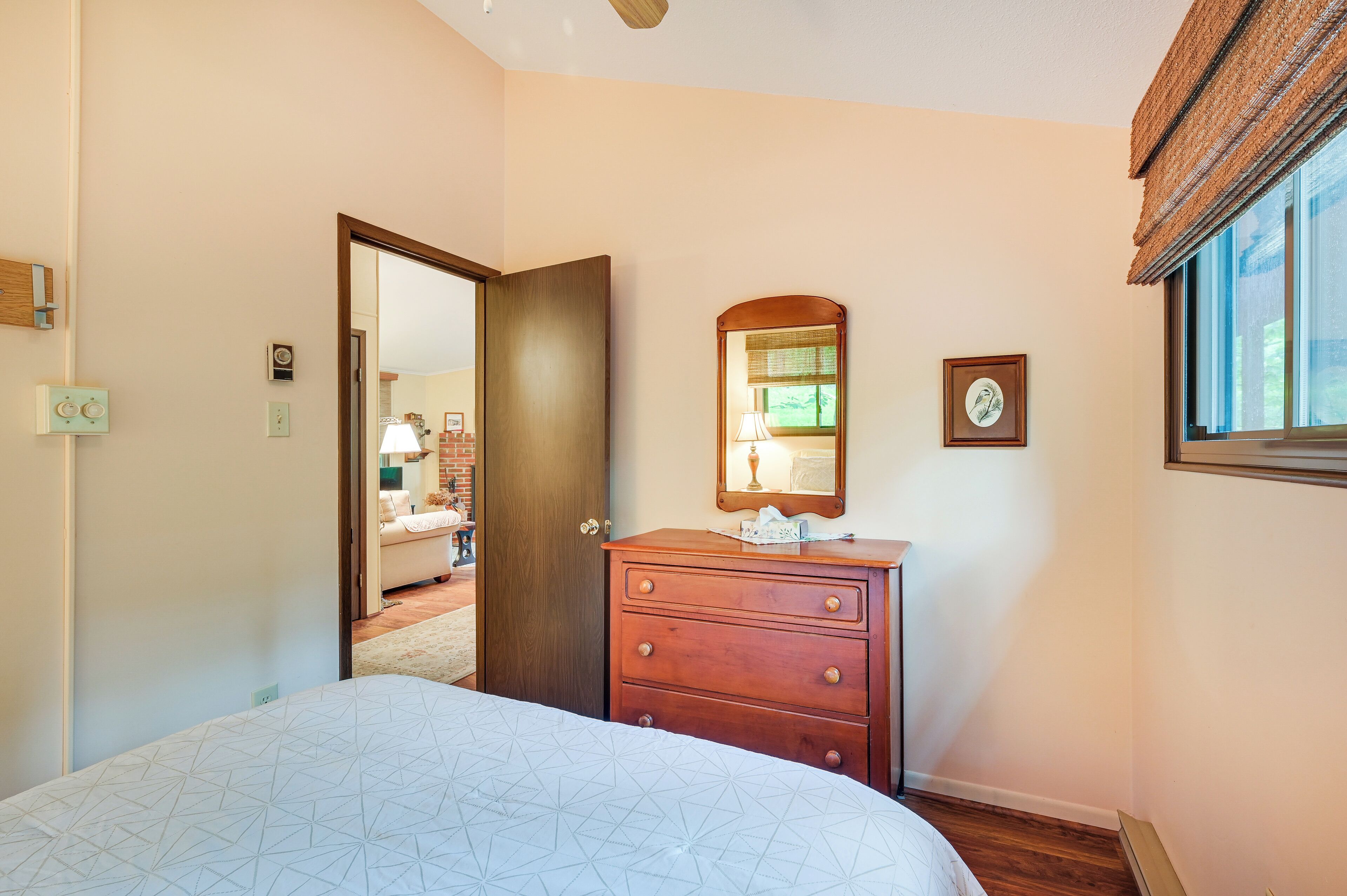 Une chambre à coucher avec un lit, une commode, un miroir et une fenêtre.