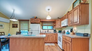 A kitchen with wooden cabinets, a central island, a refrigerator, and a microwave.