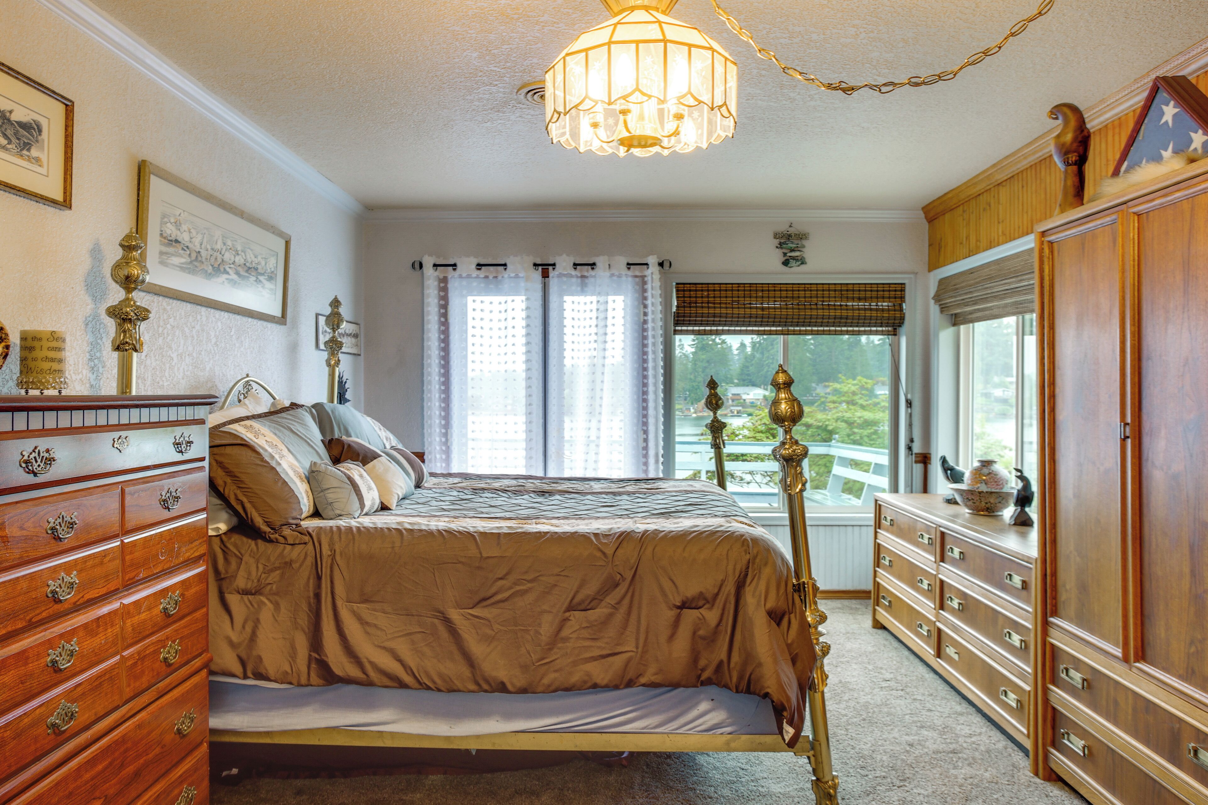 A bedroom with a bed, wooden dresser, and a chandelier.