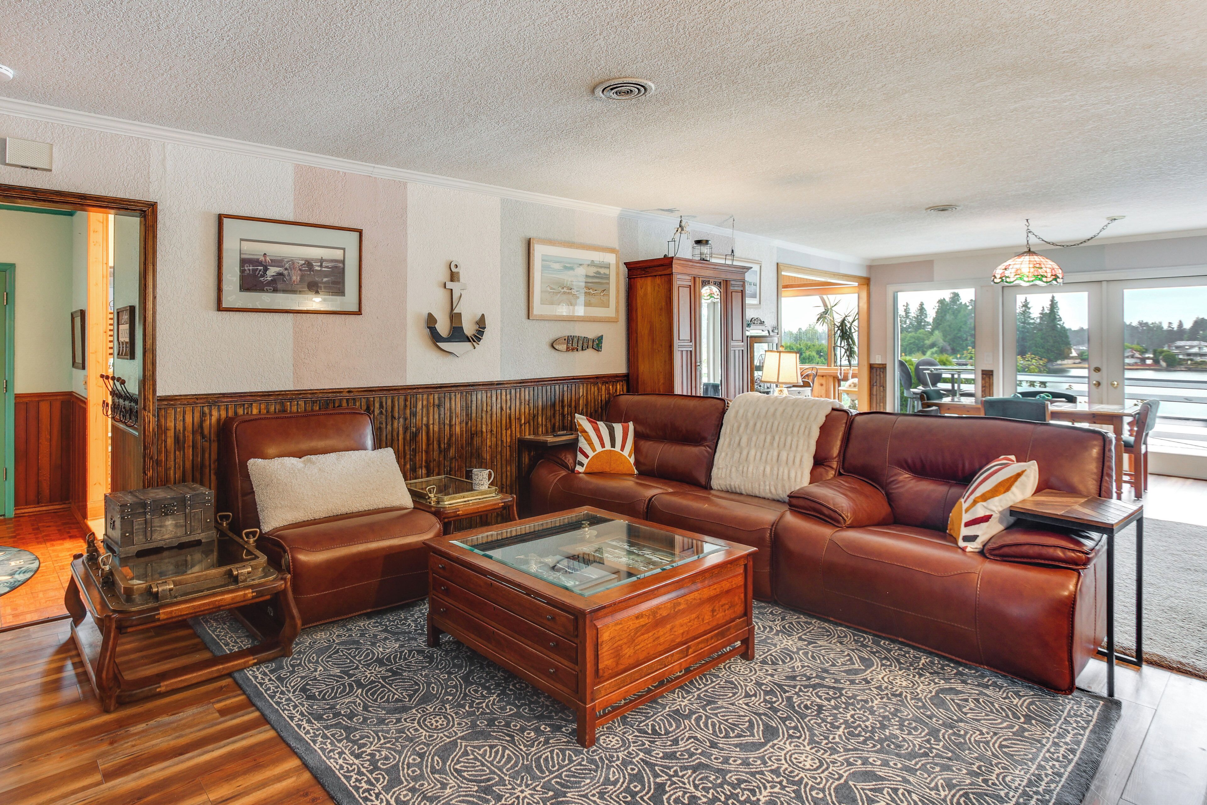 A spacious living room with a leather sofa, a glass-top coffee table, and a wooden cabinet.