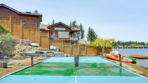 Un jardin avec une piscine, une terrasse en bois et des kayaks à proximité de l’eau.