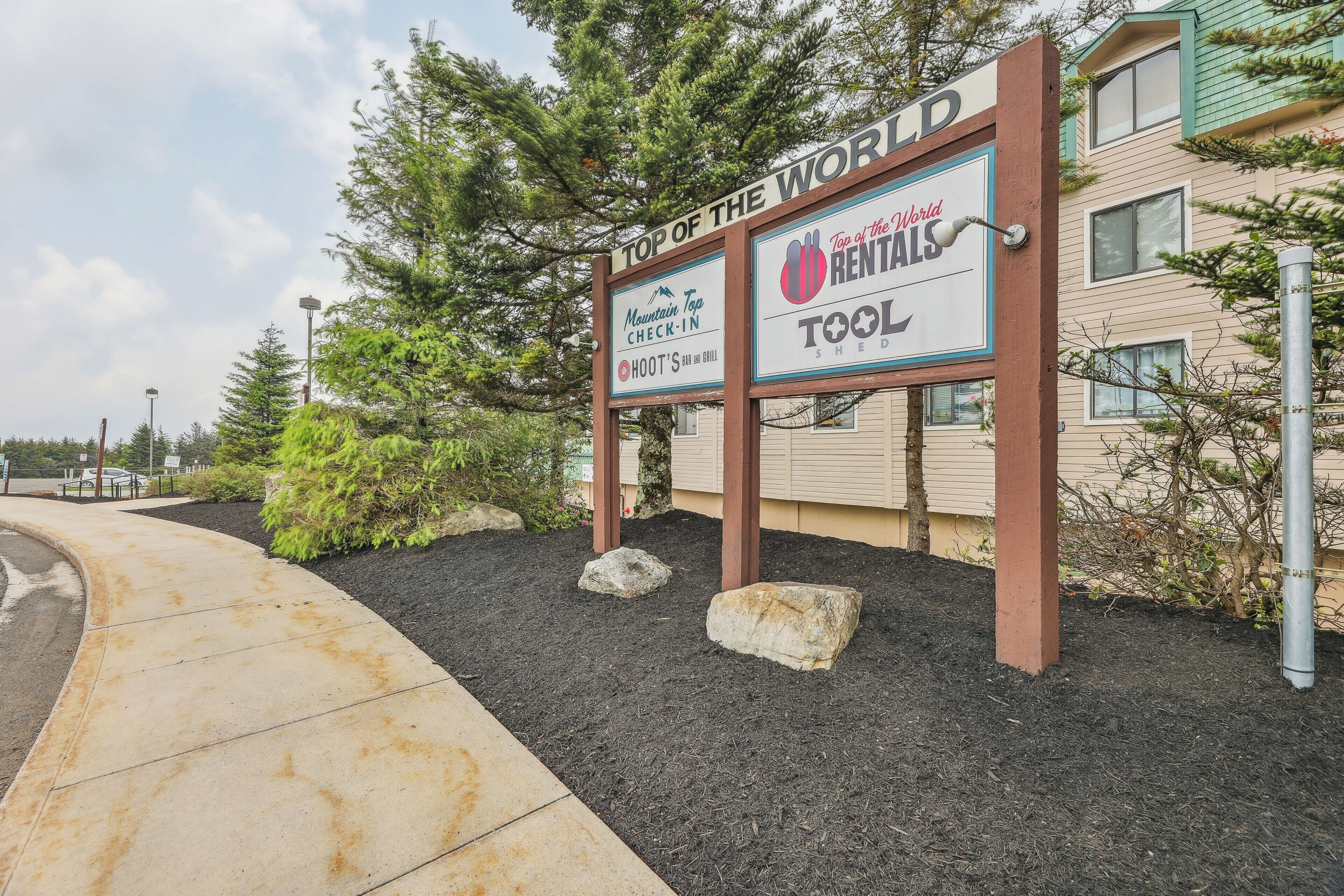A sign for a hotel named "Top of the World Rentals" with a mountain and tool logo.