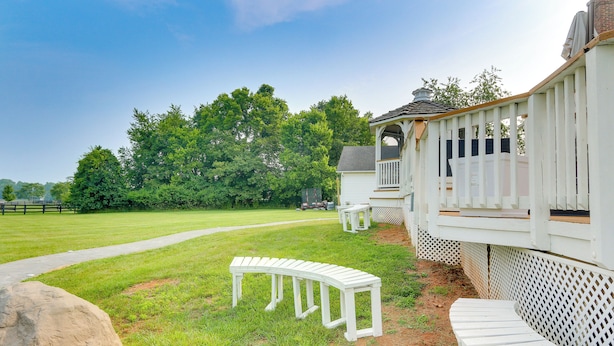 A white deck with a curved bench and a small table, surrounded by a white fence and trees in the background. - Rocky Vines Wine Country Retreat w/ Fire Pit (Leesburg)