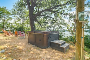 A hot tub with a wooden deck, surrounded by trees and overlooking a body of water. - Private Hot Tub & Dock: Lakefront Grove Retreat! (Grove)