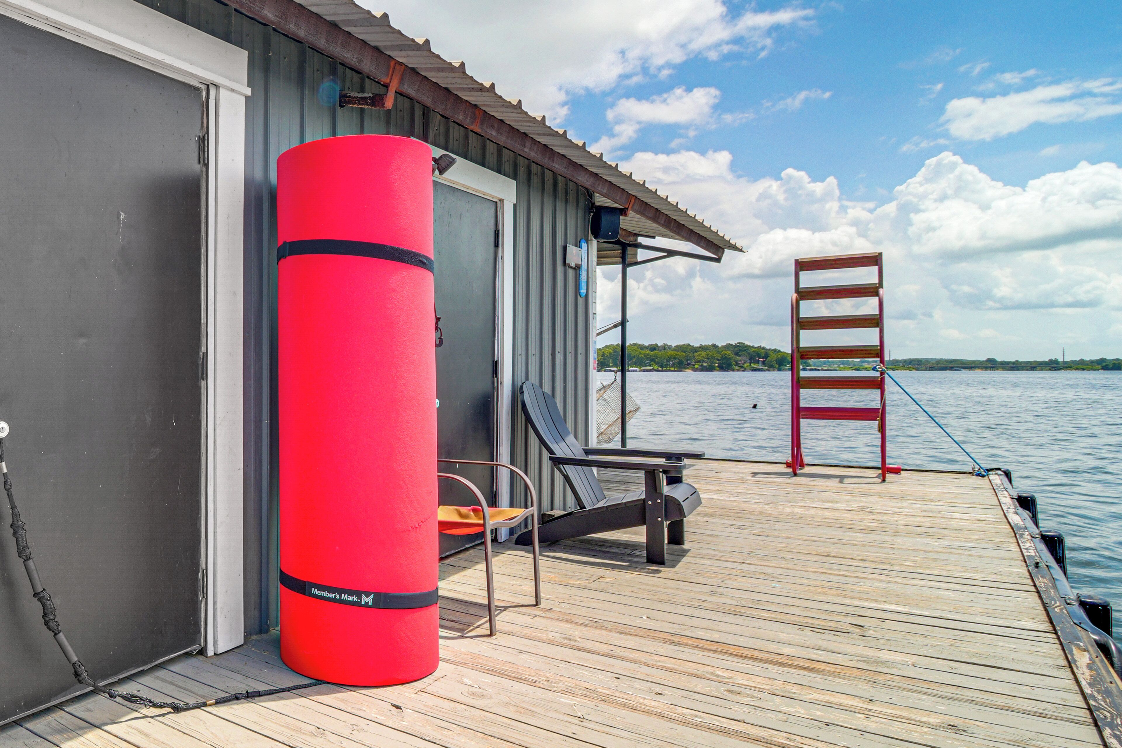 A wooden deck with a red cylindrical object, a chair, and a ladder.