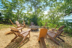 An outdoor seating area with wooden chairs and a central fire pit surrounded by trees. - Private Hot Tub & Dock: Lakefront Grove Retreat! (Grove)