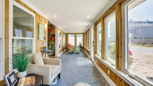 A sunlit room with a large window, a chair, a small table, and a potted plant. - Dewey Beach Cottage Near Ocean - Walk to Beach! (Dewey Beach)