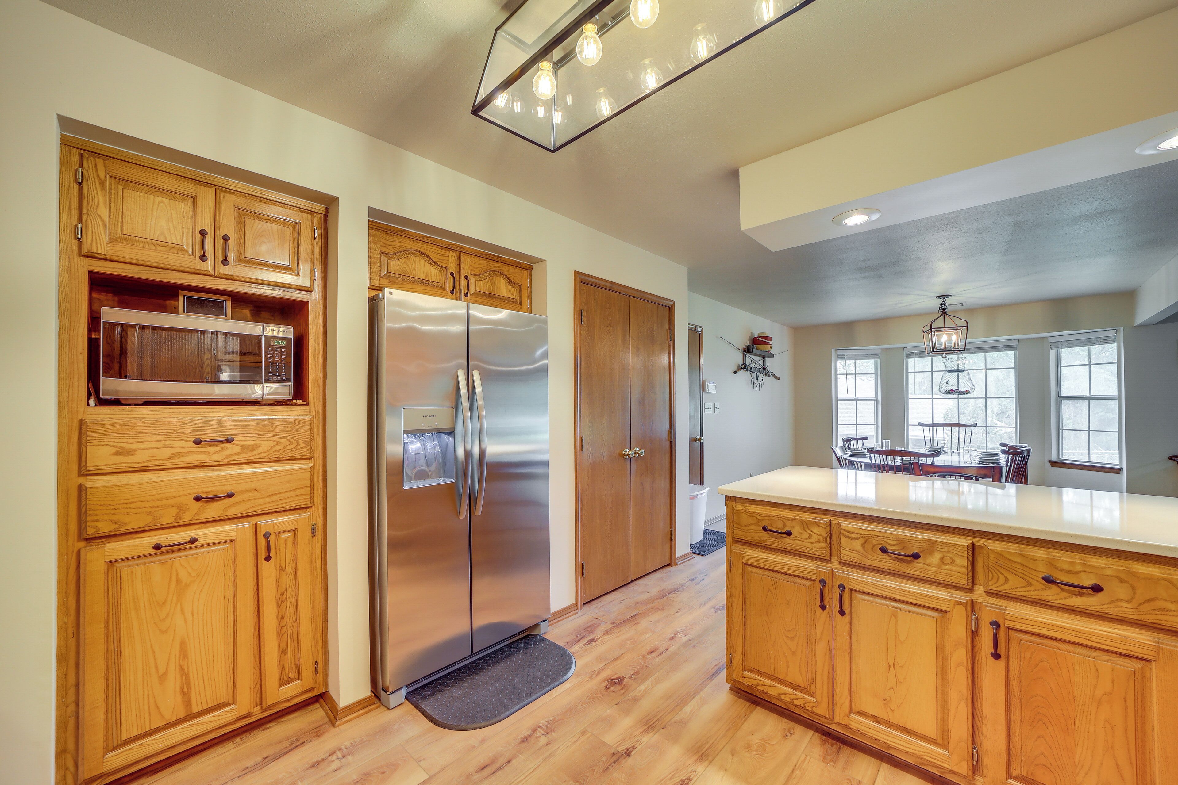 A kitchen with wooden cabinets, a stainless steel refrigerator, and a microwave.