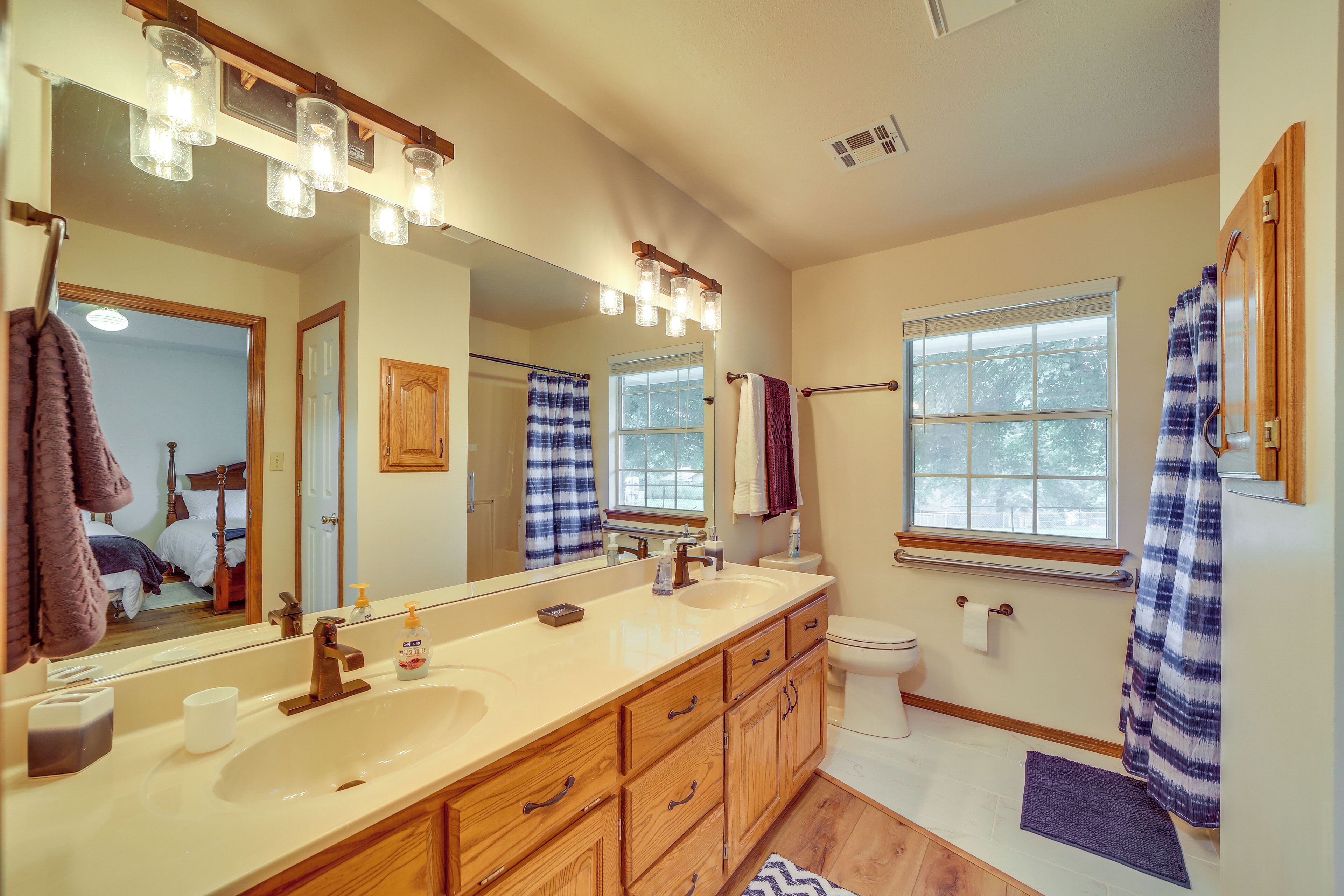 A bathroom with a large mirror, wooden cabinets, a sink, and a toilet.