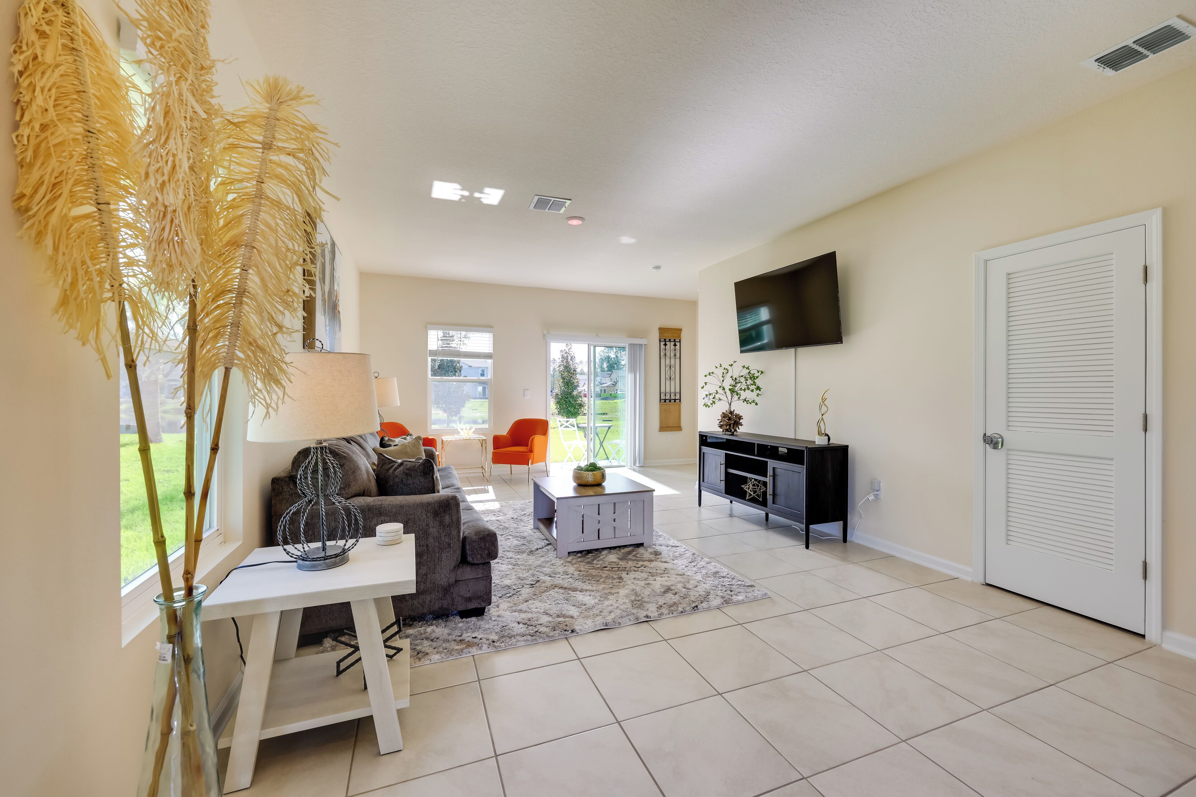 A spacious living room with a sofa, coffee table, and decorative plants.