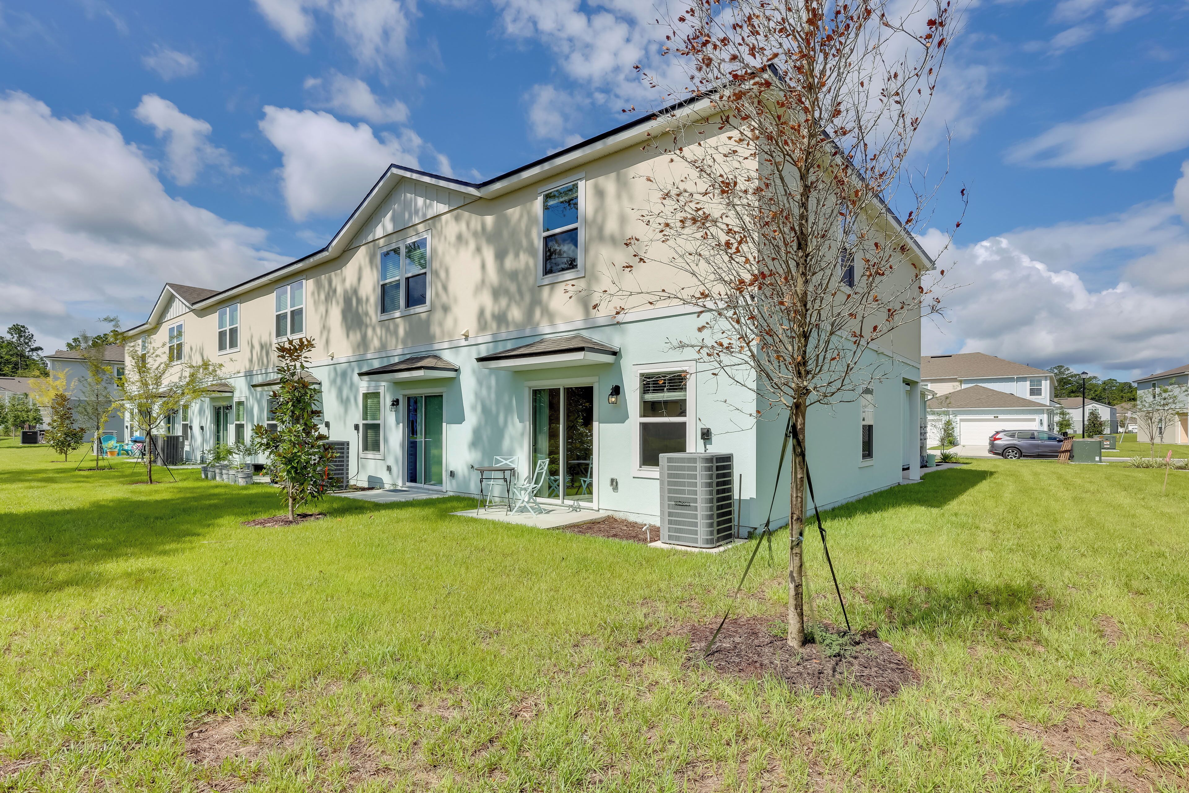 A two-story residential building with a front porch and a small tree in the yard.