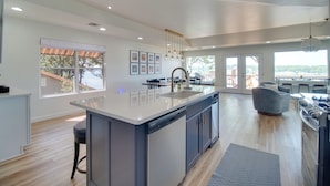 Una cocina moderna con una isla grande, suelo de madera y vistas al exterior.