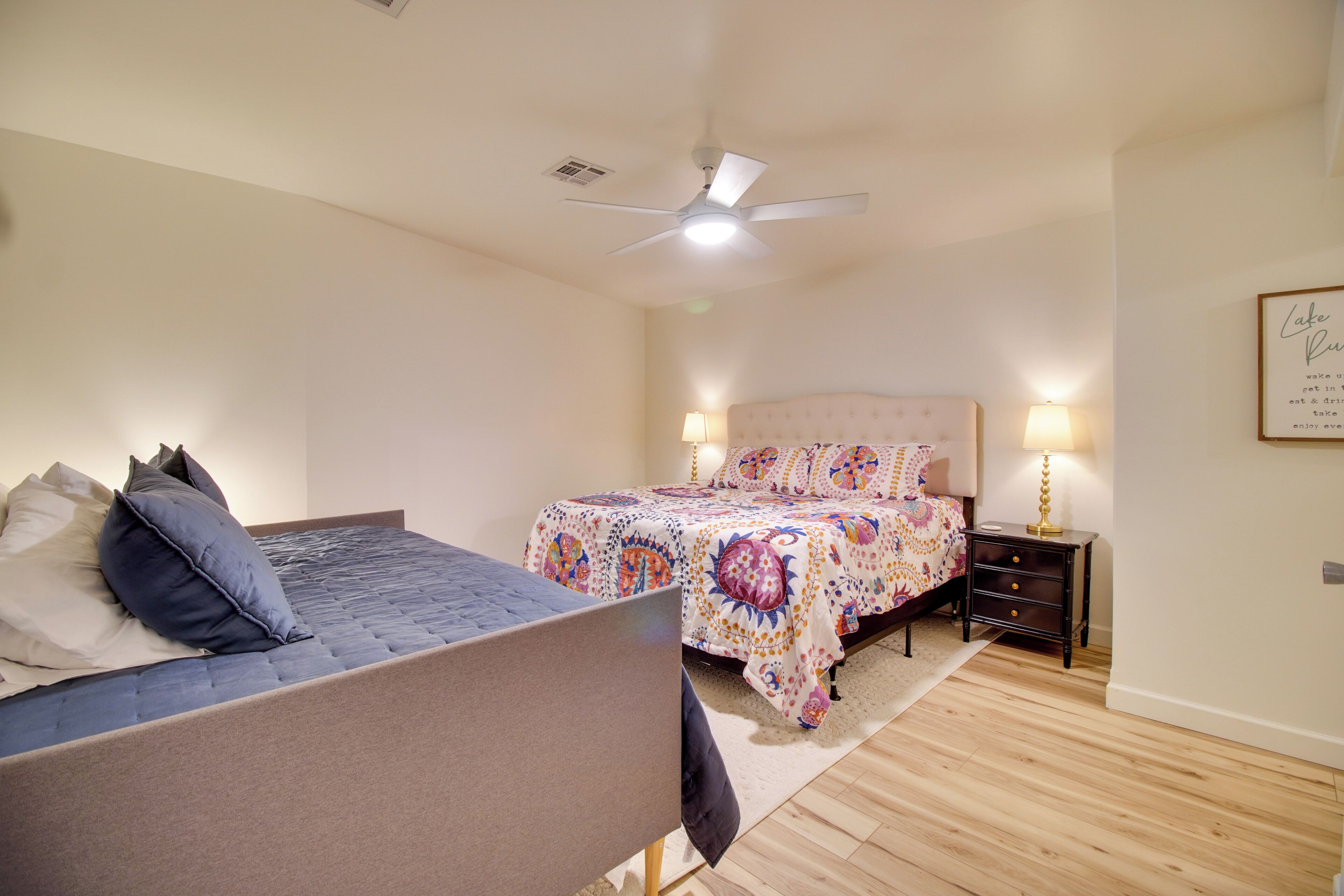 A bedroom with a bed, bedside table, lamp, and ceiling fan.