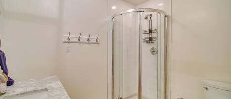 Ein Badezimmer mit Duschkabine, Marmorwaschbecken und Toilette.