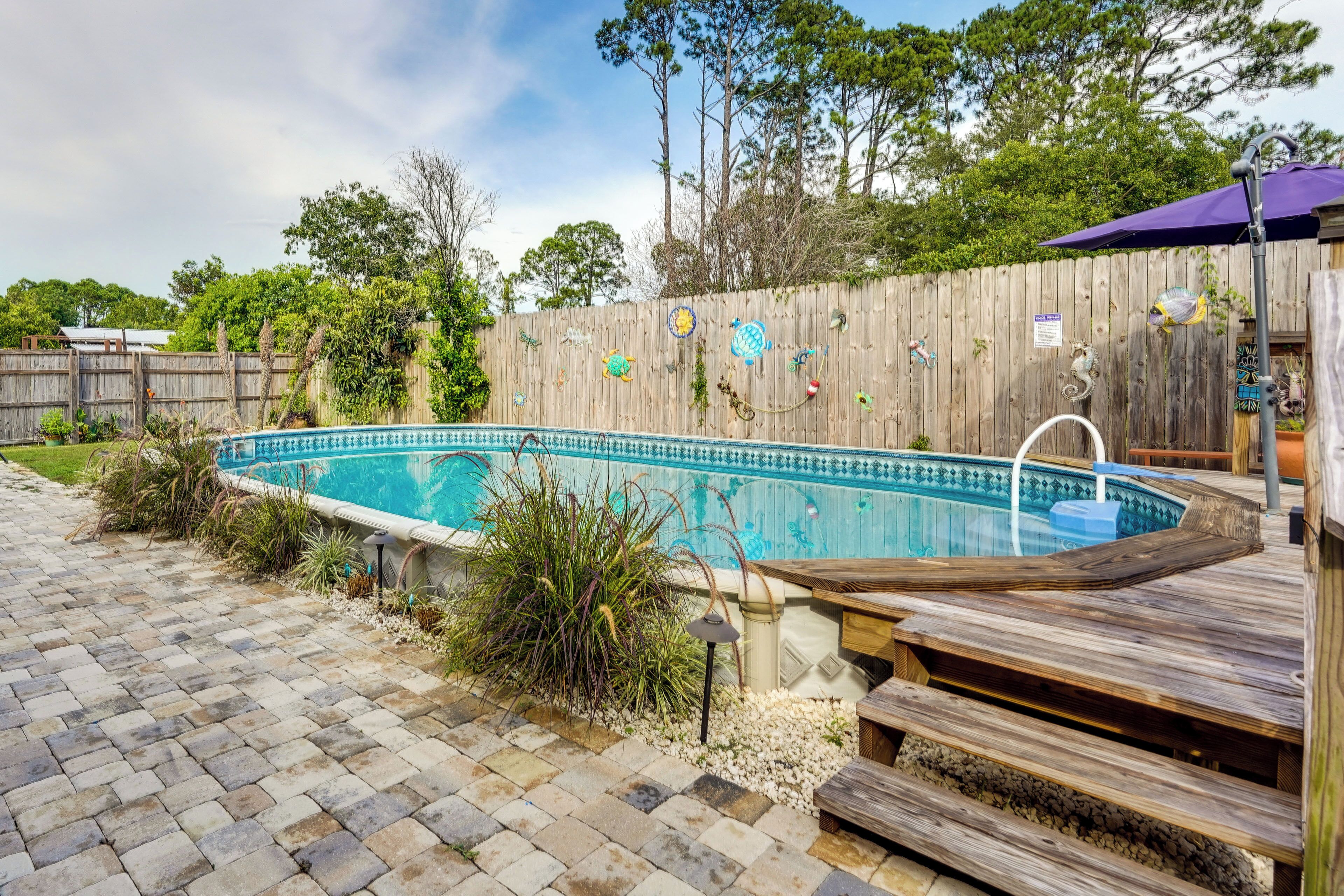 A swimming pool with a wooden deck and a wooden fence with decorative elements.