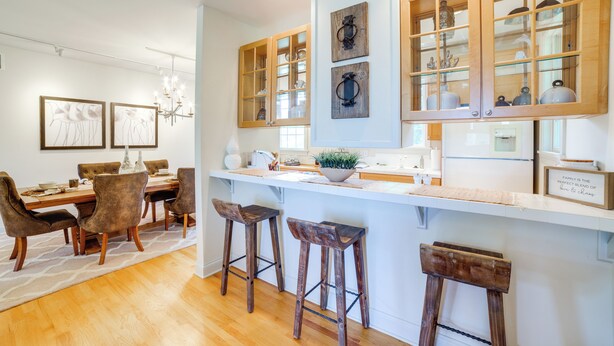 A modern kitchen with wooden cabinets, a dining area with a chandelier, and a bar stool setup. - 1 Mi to Indiana Dunes NP: Spacious Gary Home! (Gary)