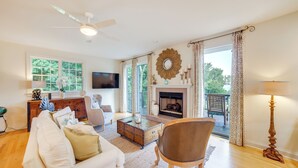 A spacious living room with a fireplace, a ceiling fan, and a large window. - 1 Mi to Indiana Dunes NP: Spacious Gary Home! (Gary)