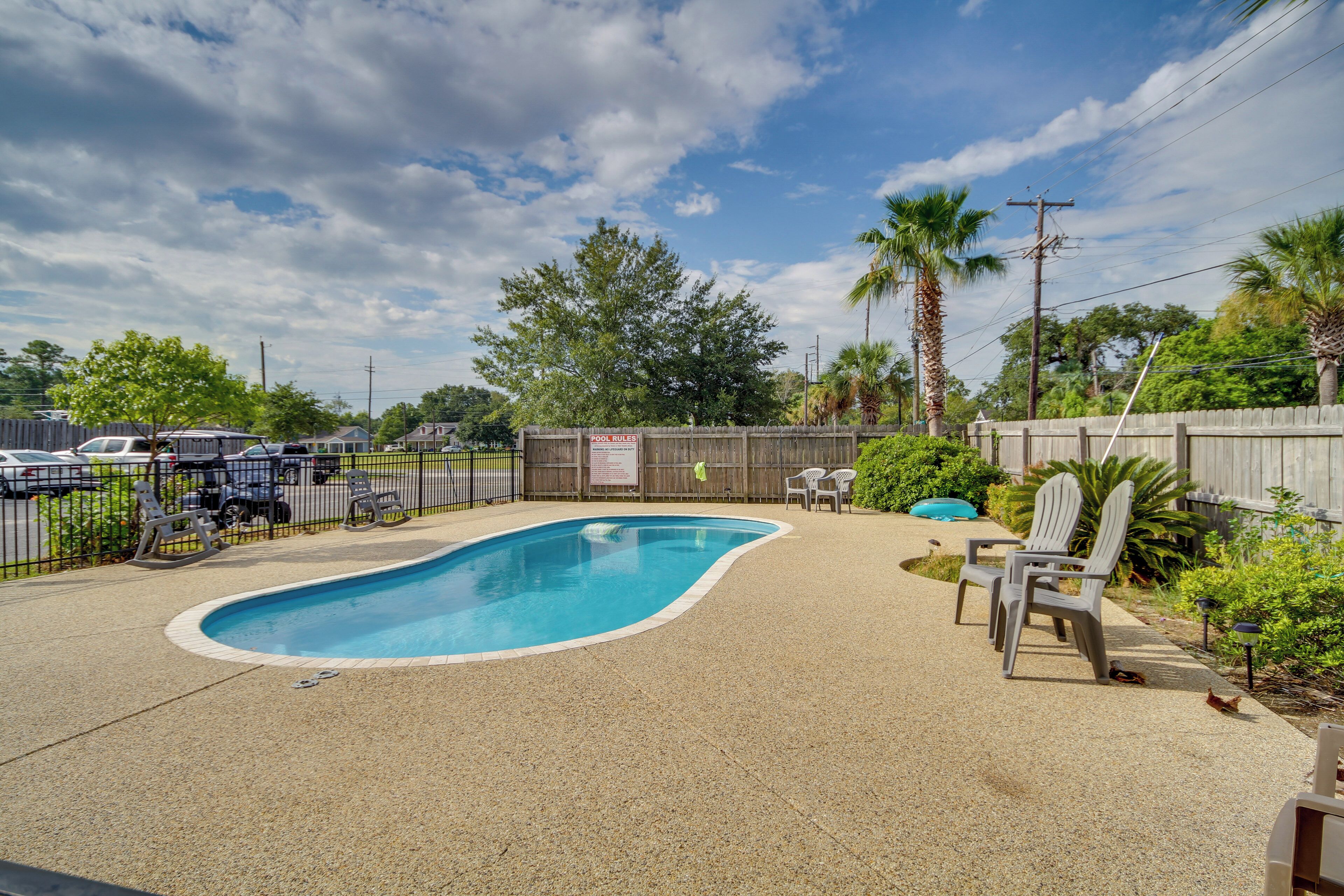 A backyard with a swimming pool, a wooden fence, and outdoor furniture.
