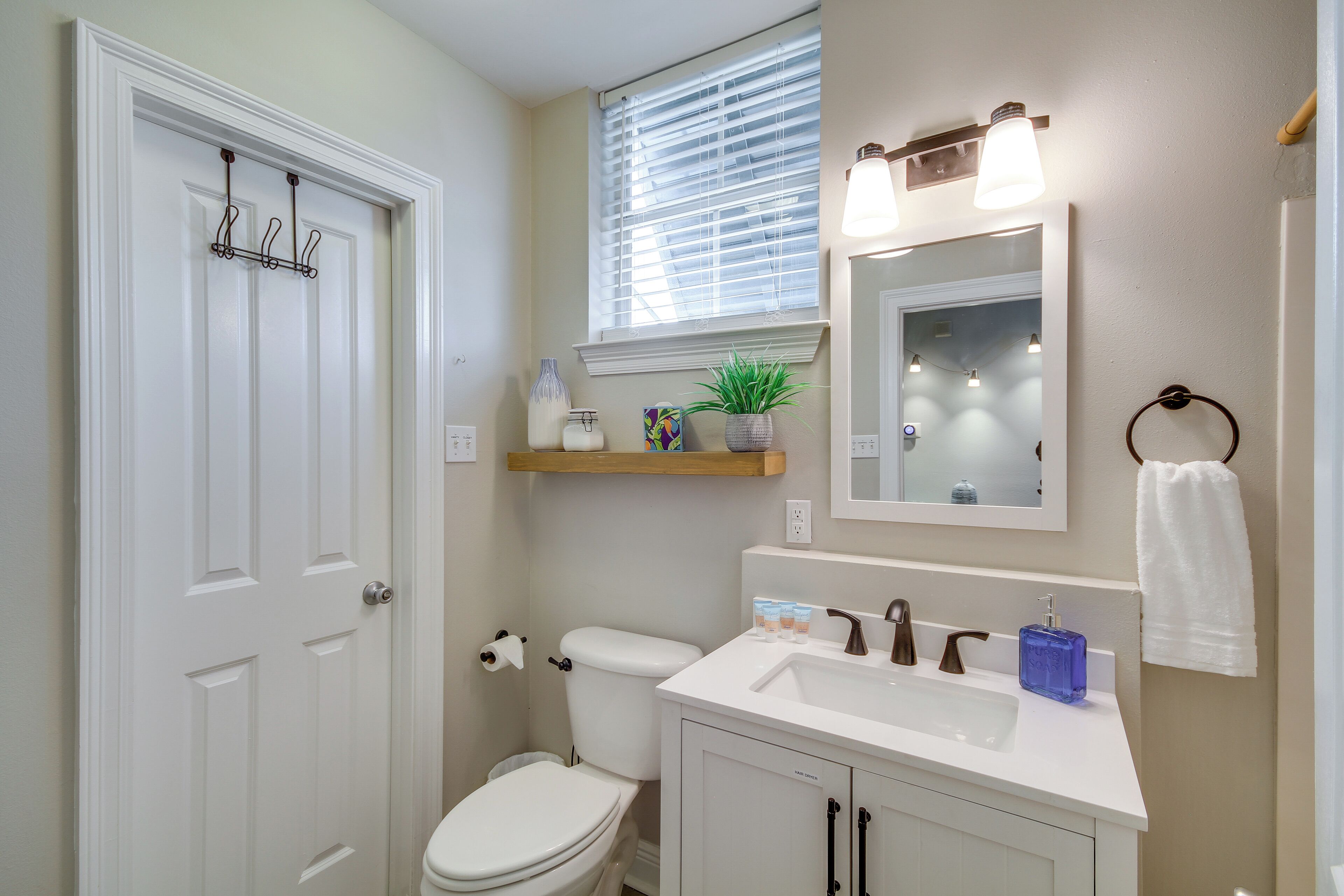 A bathroom with a white toilet, a sink with a mirror above it, and a towel hanging on a ring.